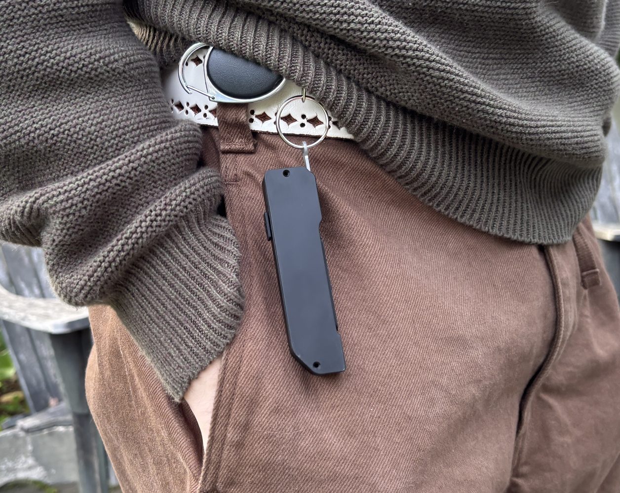 Glance clipped vertically to a belt beside a trouser pocket.